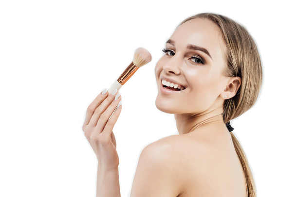 Natural beauty. Smiling and beautiful woman on a white background with a makeup brush looking at the camera. Clean and healthy skin, beauty salon, facial skin care. - Foto, immagini