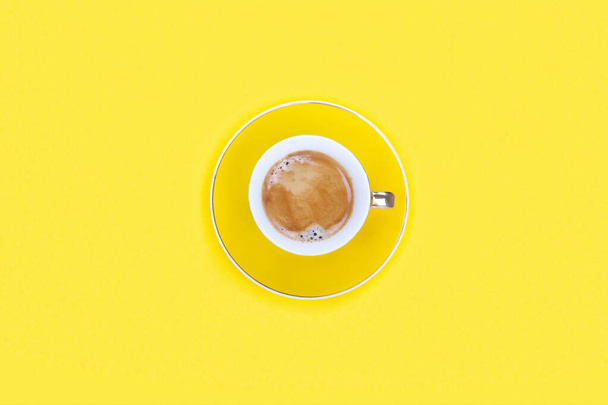 Flache Tasse Kaffee auf gelbem Hintergrund mit Kopierraum. Konzeptfrühstück. - Foto, Bild