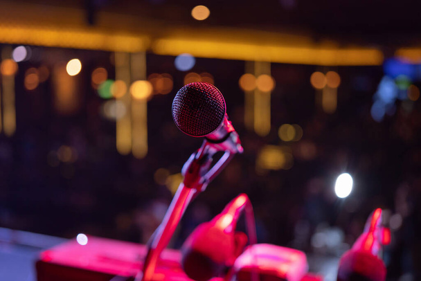 Un micrófono en el escenario concierto con iluminación de colores espectáculo de rayos láser en discoteca club bar fondo para la fiesta espectáculo de música bailando festival. Vida nocturna de entretenimiento. Evento de celebración - Foto, imagen