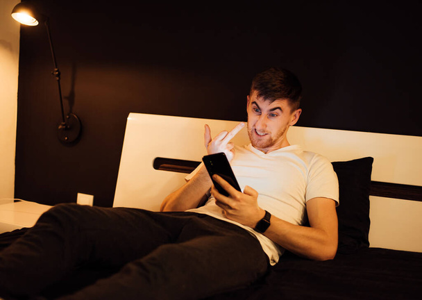 young man relaxing on bed,using smartphone - Foto, Bild