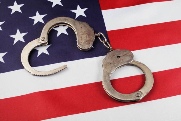 поліцейські наручники на прапорі США крупним планом
  - Фото, зображення