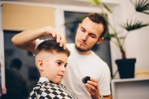 barber grooming cute little boy at hair salon - Foto, immagini