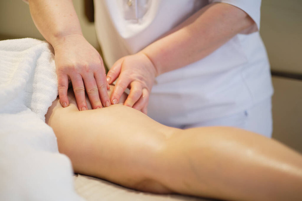 Concepto de cuidado corporal. Tratamiento especial contra la celulitis. Masajista hace anticelulitis masaje mujer joven en el salón de spa. Vista de cerca - Foto, Imagen