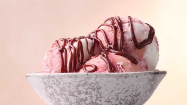 zbliżenie obracającej się miski kulek lodowych ozdobionych sosem czekoladowym i kolorowymi posypkami cukru - Materiał filmowy, wideo