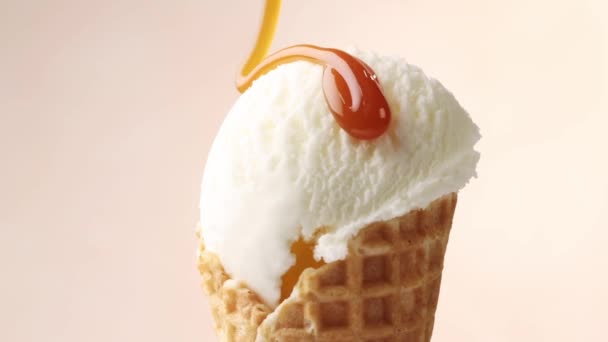 gesmolten karamelsaus stromend op draaiend vanille-ijs in wafelschep close-up - Video