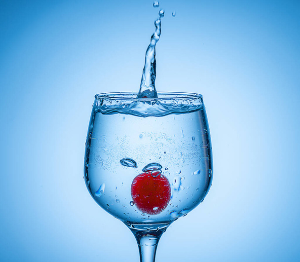Цветной ледяной шар упал в стакан для коктейлей . - Фото, изображение