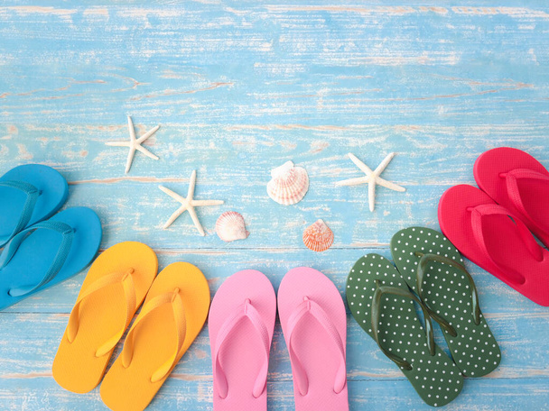 Beach accessories on blue wooden plank, summer holiday on the beach concept, colorful sandals with seashell and starfish - Фото, изображение