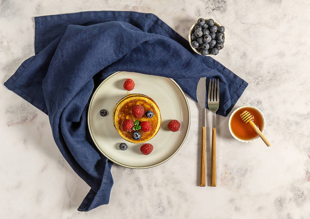 Tasty american pancakes with raspberries, blueberries, and honey. Top view, marble table. - Foto, afbeelding