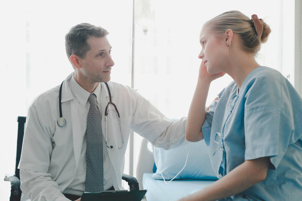 Doctor doing a physical examination of the young beautiful patient and explaining health problems to the patient who setting on the hospital bed, health care and hospital concept - Photo, Image