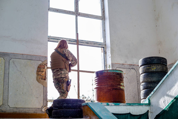 Ragazza in uniforme militare con una pistola airsoft in un edificio abbandonato - Foto, immagini