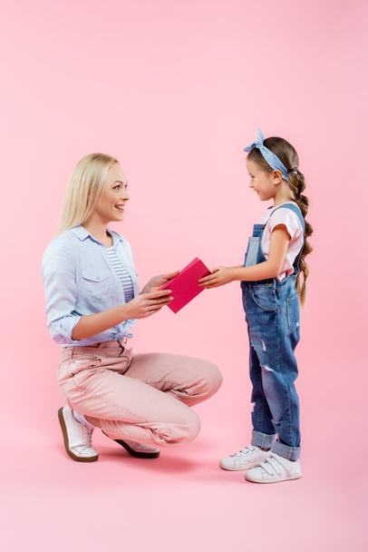happy mother receiving greeting card from daughter on pink - Фото, зображення