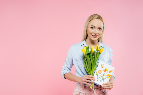 happy woman holding tulips and greeting card isolated on pink  - Фото, изображение
