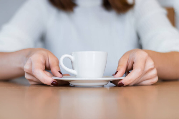 A nő a fa asztalon török kávét tart a kezével. - Fotó, kép