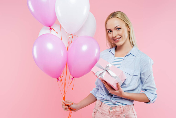 happy woman holding balloons and gift box isolated on pink - Foto, afbeelding