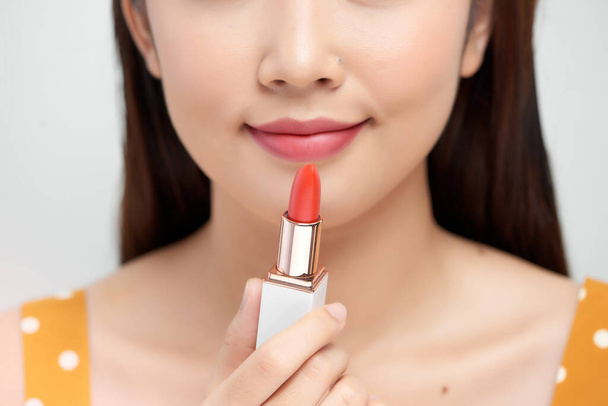 Belle jeune femme tenant un rouge à lèvres rouge, isolé sur fond blanc - Photo, image