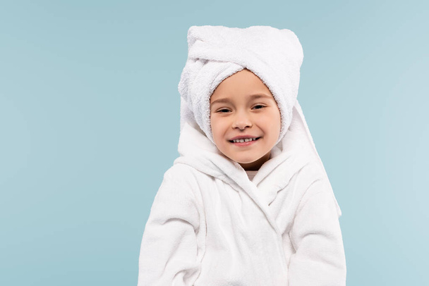 bambino felice in accappatoio avvolto in asciugamano sorridente isolato su blu - Foto, immagini
