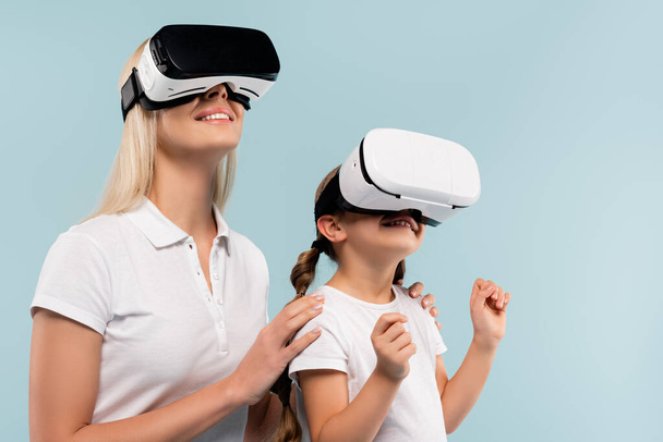 cheerful mother and happy kid in vr headsets isolated on blue - Foto, imagen