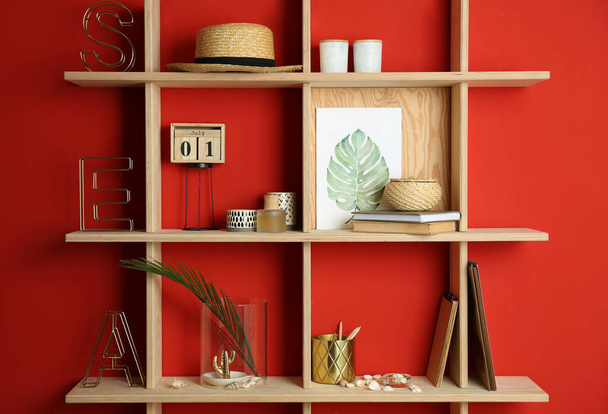 Stylish wooden shelves with decorative elements on red wall - Zdjęcie, obraz