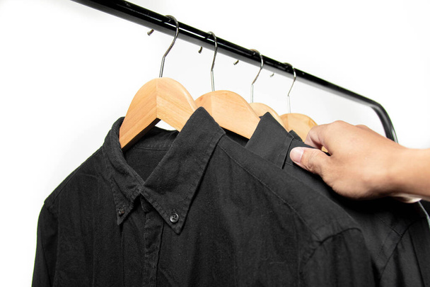 A businessman chooses shirt on the black hanger before go to work or before a night out. Choose a cotton black shirt - Fotografie, Obrázek