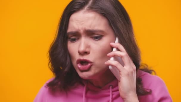 mujer molesta quejándose mientras habla en el teléfono inteligente aislado en amarillo - Metraje, vídeo