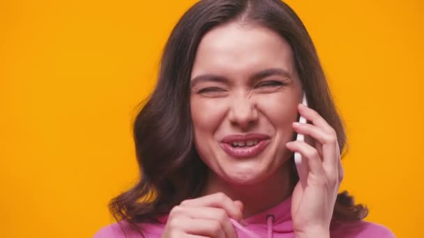 jovem mulher alegre falando no smartphone isolado no amarelo - Filmagem, Vídeo