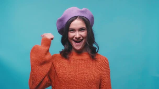 glückliche Frau in Baskenmütze zeigt Daumen nach oben vereinzelt auf blau - Filmmaterial, Video