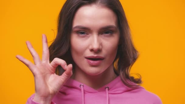 young happy woman showing ok sign isolated on yellow - Footage, Video