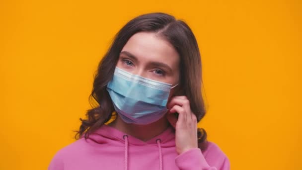 mulher feliz tirando máscara médica e sorrindo isolado no amarelo - Filmagem, Vídeo