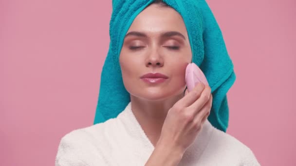 vrouw met behulp van siliconen reinigingsmiddel gadget op gezicht geïsoleerd op roze - Video