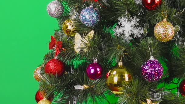Auf grünem Hintergrund großer schöner Weihnachtsbaum mit buntem Spielzeug geschmückt  - Filmmaterial, Video