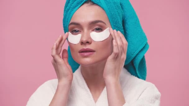 νεαρή γυναίκα εφαρμογή μπαλώματα μάτι απομονώνονται σε ροζ - Πλάνα, βίντεο