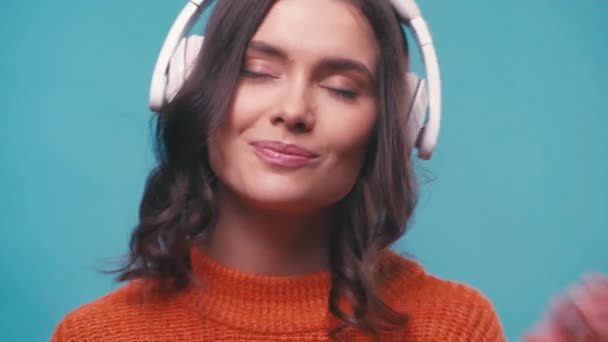 mujer complacida en auriculares inalámbricos escuchando música aislada en azul - Metraje, vídeo