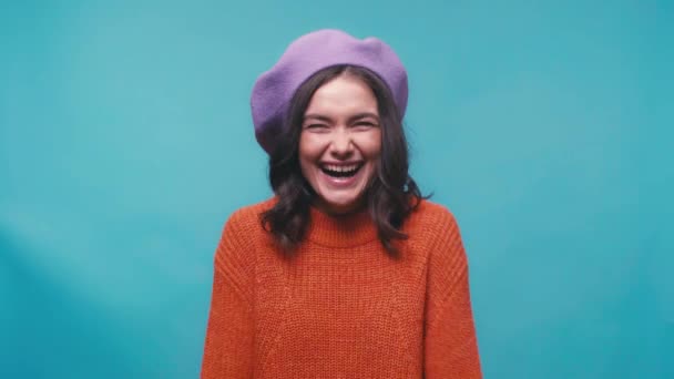 cheerful young woman in beret laughing isolated on blue - Πλάνα, βίντεο