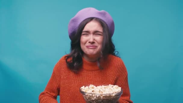 mujer feliz en boina comiendo palomitas de maíz y viendo películas en azul - Metraje, vídeo