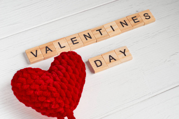 Κάτοψη της λέξης valentines ημέρα που έξω από την πλατεία ξύλινα κεραμίδια και κόκκινο μεγάλο πλεκτό καρδιές σε παλιό λευκό ξύλινο φόντο. Επιλεκτική εστίαση - Φωτογραφία, εικόνα
