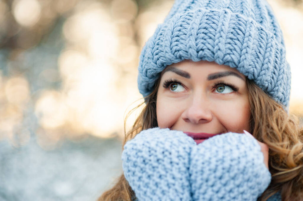 closeup portrait of attractive caucasian smiling woman brunette outdoors smile face hair head and shoulders winter christmas. Model looking aside, wearing stylish sweater, hat, gloves. - Photo, Image