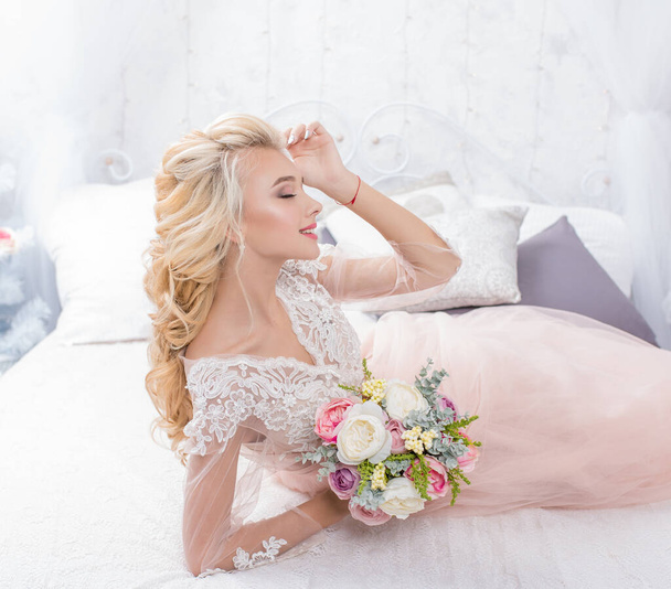 Νεαρή νύφη μόδας ομορφιάς στη χειμερινή διακόσμηση με μπουκέτο λουλούδια στα χέρια της. Όμορφη νύφη πορτρέτο γάμου μακιγιάζ και χτένισμα. Μόδα νύφη μοντέλο σε πολυτελές νυφικό. - Φωτογραφία, εικόνα