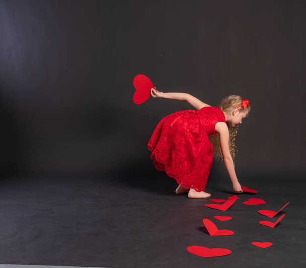 paper hearts, Valentines day board, hearts on the floor . the holiday form. copy space formula of love, engagement in a red dress girl, barefoot - Foto, afbeelding