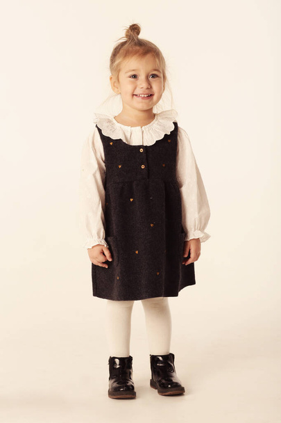 мила маленька блондинка дівчинка в чорній сукні портрет повного тіла ізольовано на білому
 - Фото, зображення