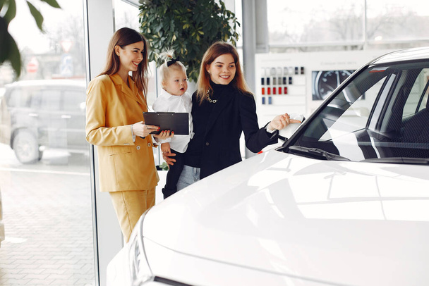 Elegant woman with little daughter in a car salon - Фото, изображение
