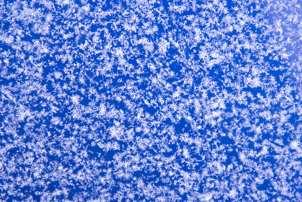 There are white snowflakes on the blue surface. Background, texture of snow. Soft focus - Photo, image