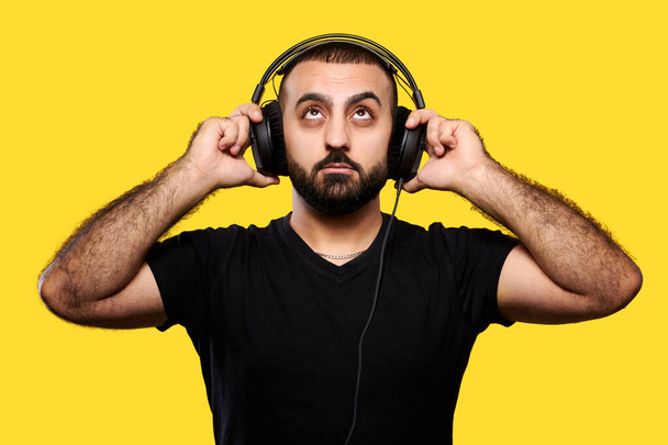 Positive bearded DJ with headphones laughing on a yellow background. Enjoy your music. International DJ Day. - Photo, Image
