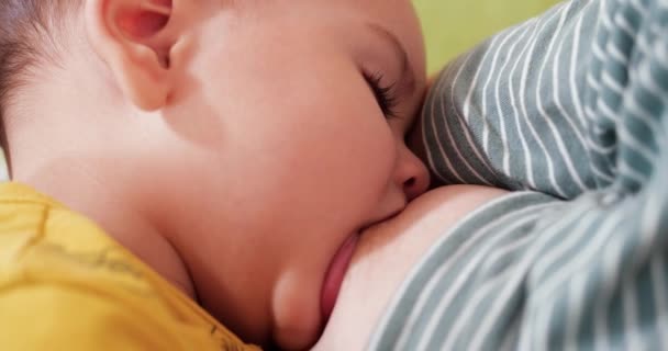Moeder die haar pasgeboren baby borstvoeding geeft op de bank. Melk van moeders borst is een natuurlijk medicijn voor de baby. familie, voedsel, kind, eten en ouderschap concept - Video