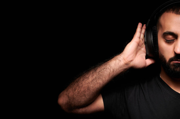 国際DJ日のヘッドフォンで髭のミュージシャンは黒の背景に音楽を聴く - 写真・画像