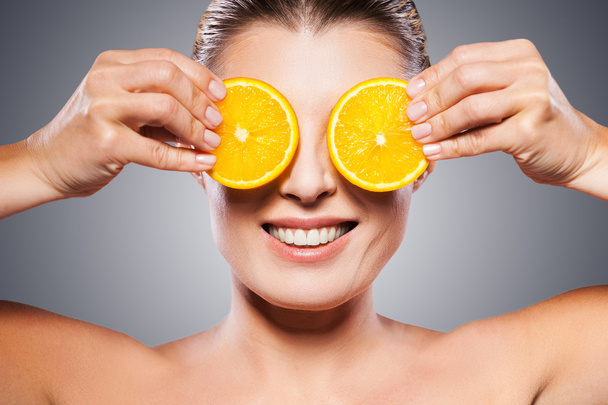 Woman holding pieces of orange in front of eyes - Foto, Bild