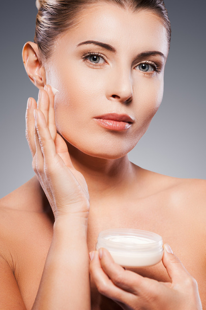 Mature woman spreading cream on face - Photo, Image
