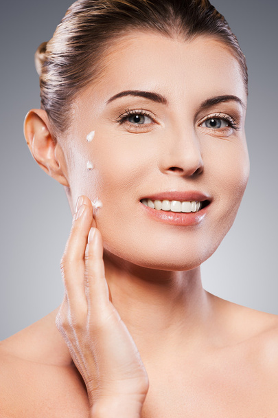 Mature woman spreading cream on face - Photo, image