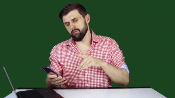 un blogueur technologique masculin parle de gadgets et de gestes avec ses mains sur le fond d'un chromakey - Séquence, vidéo