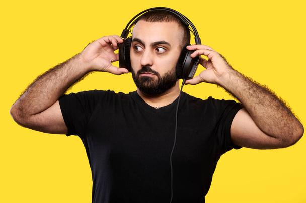 Yllättynyt arabialainen muusikko DJ jolla on parta kuuntelee musiikkia kuulokkeilla. Kansainvälinen DJ-päivä - Valokuva, kuva