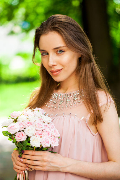 Close up portrait of a young cheerful girl in pink dress in summer street - Фото, зображення
